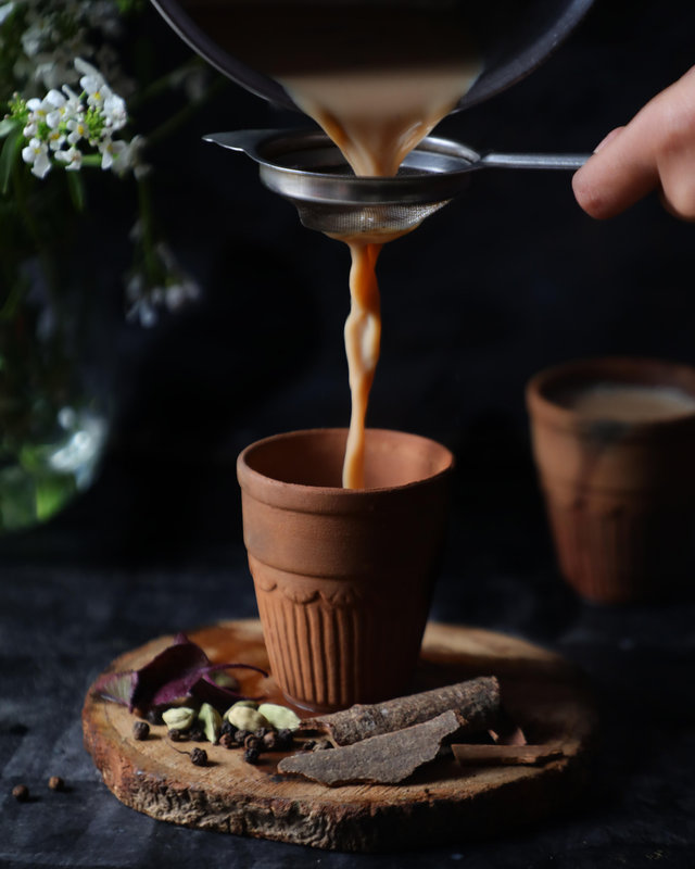 Caffeine-free masala chai poured through a strainer into a terracotta cup